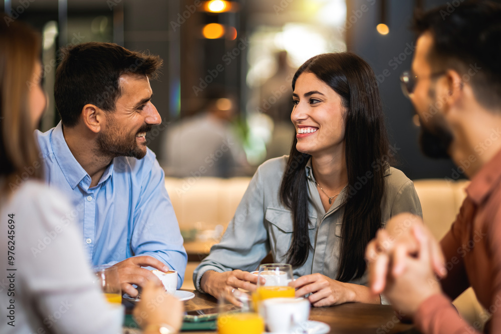 Group of friends met at the cafe. Drinking coffee and orange juice. Girl and guy are talking while the other friends are listening to them. Group of friends met at the cafe. Drinking coffee and orange juice. Girl and guy are talking while the other friends are listening to them.