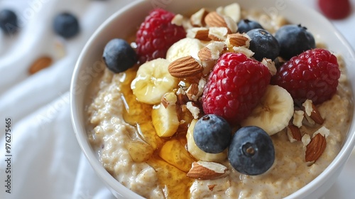 Close-up of a bowl of oatmeal with banana, raspberries, blueberries, almonds and honey.