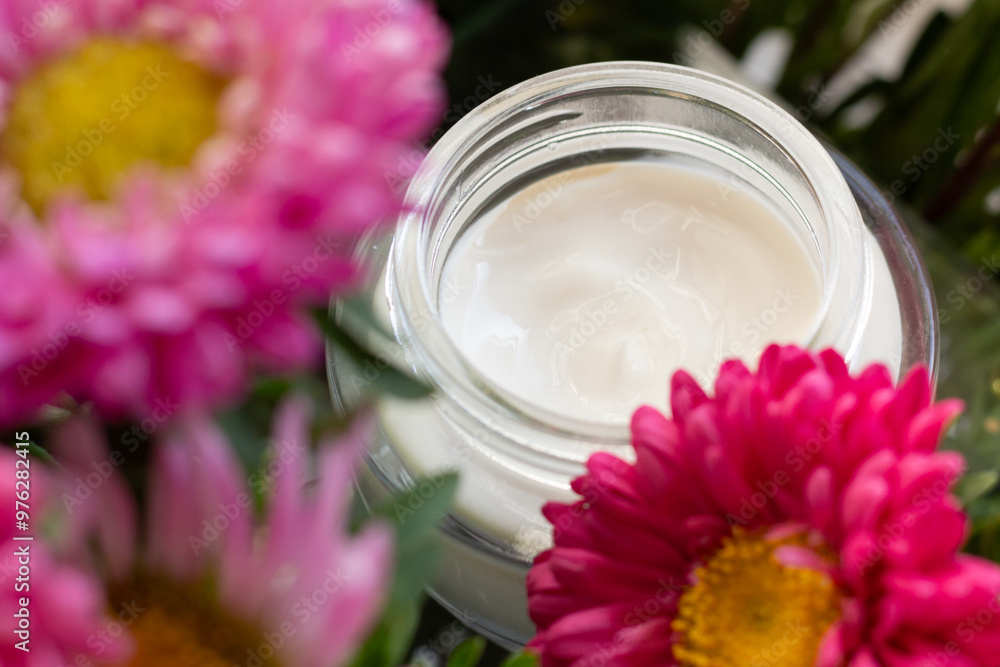 Closeup of a jar of moisturizer surrounded by flowers. Concept of spring skincare.