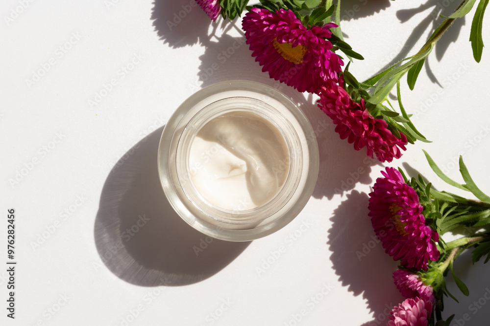 Closeup of a jar of moisturizer surrounded by flowers. Concept of spring skincare.