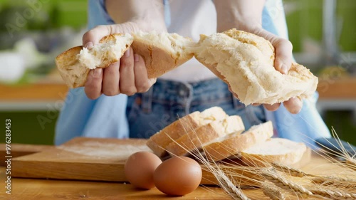 Woman baker breaking crusty bread, showing fresh bakery, close up