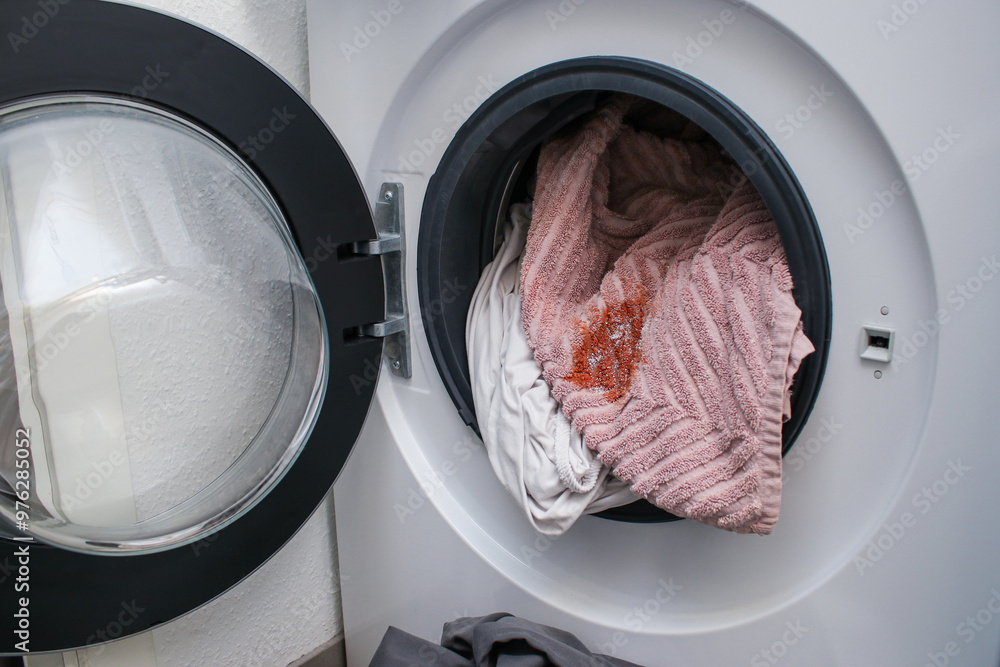 Dirty cloth with a red spot in a washing machine Dirty cloth with a red spot in a washing machine