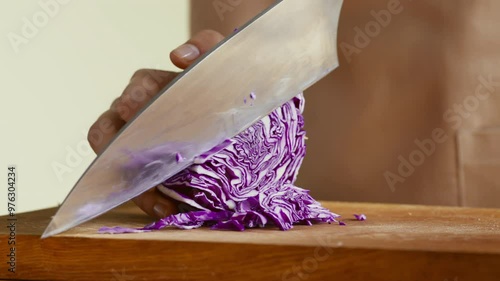 Clean eating concept. Woman with big knife cutting purple cabbage at kitchen