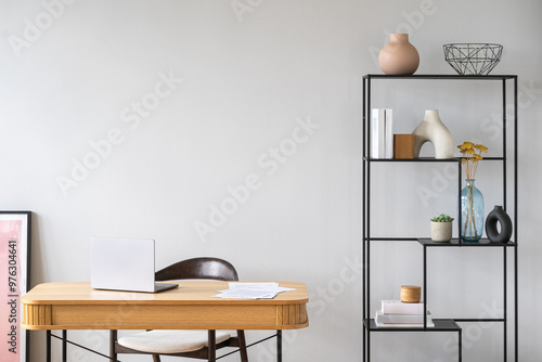 Tapeta Wooden desk with laptop close to minimalist decor on black shelving