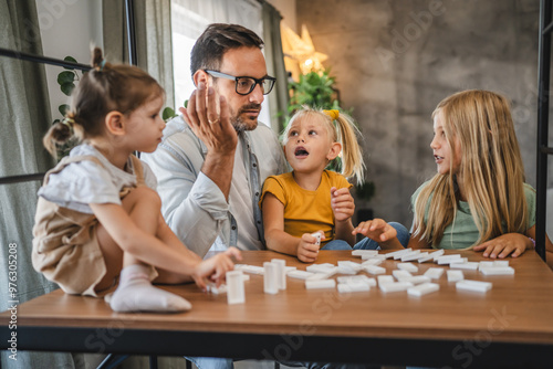 Single father play dominoes with his three young daughters at home