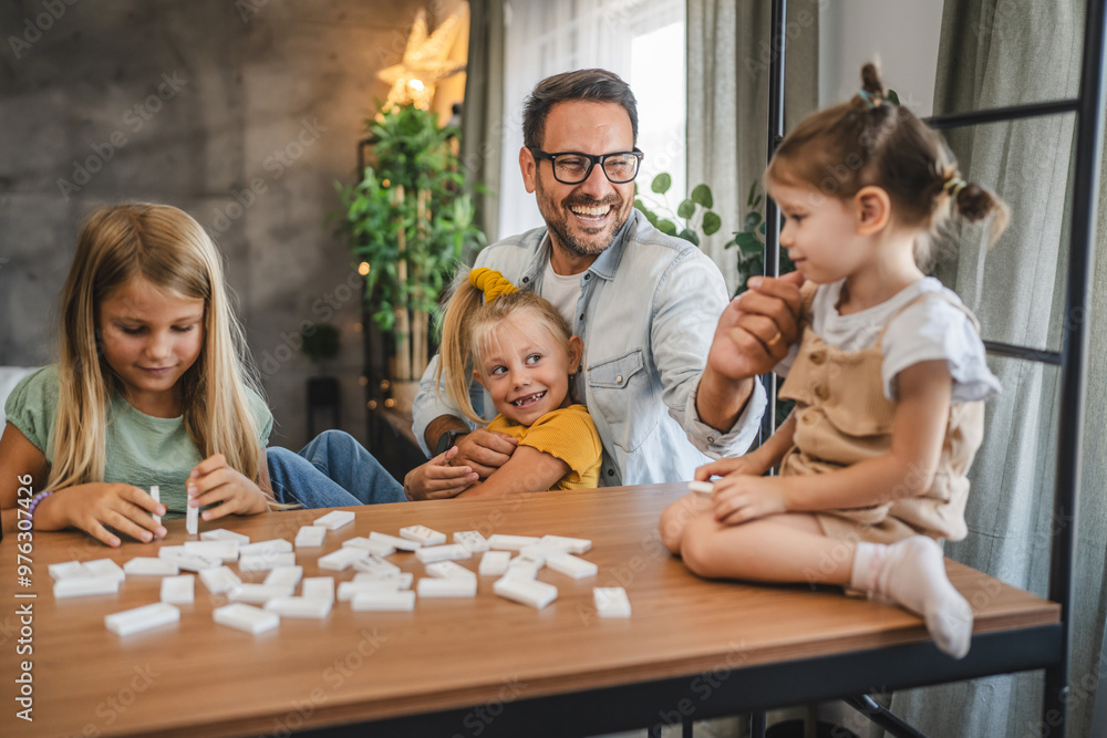 Single father play dominoes with his three young daughters at home Single father play dominoes with his three young daughters at home