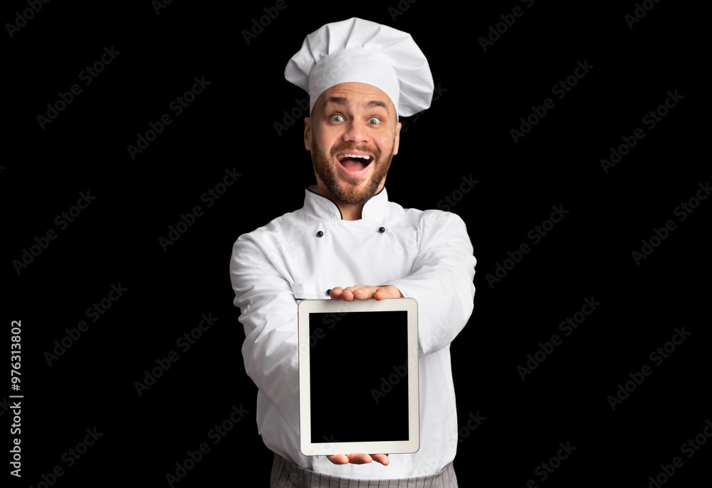 Excited Chef Showing Digital Tablet With Empty Screen Recommending Restaurant Menu Or Food Delivery Service Posing On Black Studio Background. Excited Chef Showing Digital Tablet With Empty Screen Recommending Restaurant Menu Or Food Delivery Service Posing On Black Studio Background.
