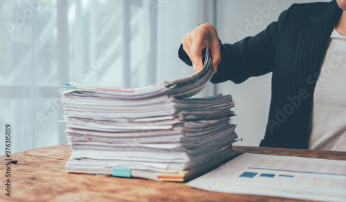 Photos Overwhelmed: A Mountain of Paperwork Awaits - A businesswoman faces a daunting stack of documents, highlighting the pressures of a demanding workload in today's fast-paced business environment