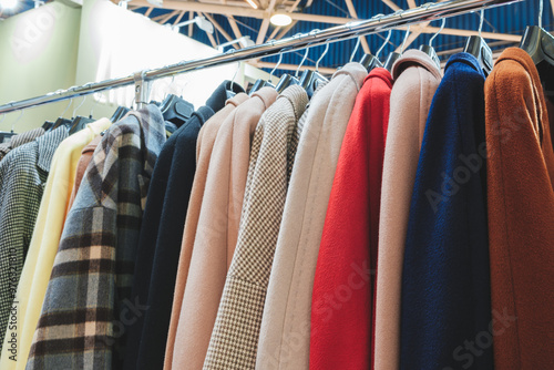 A rack of clothes with a variety of colors and patterns. The clothes are hanging on a rack, and the colors include black, red, blue, and yellow photo