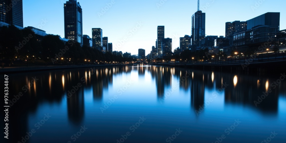 Naklejka premium A beautiful city skyline reflected on calm water during twilight, highlighting the serene atmosphere, urban architecture, and the beauty of cityscapes at dusk or dawn.
