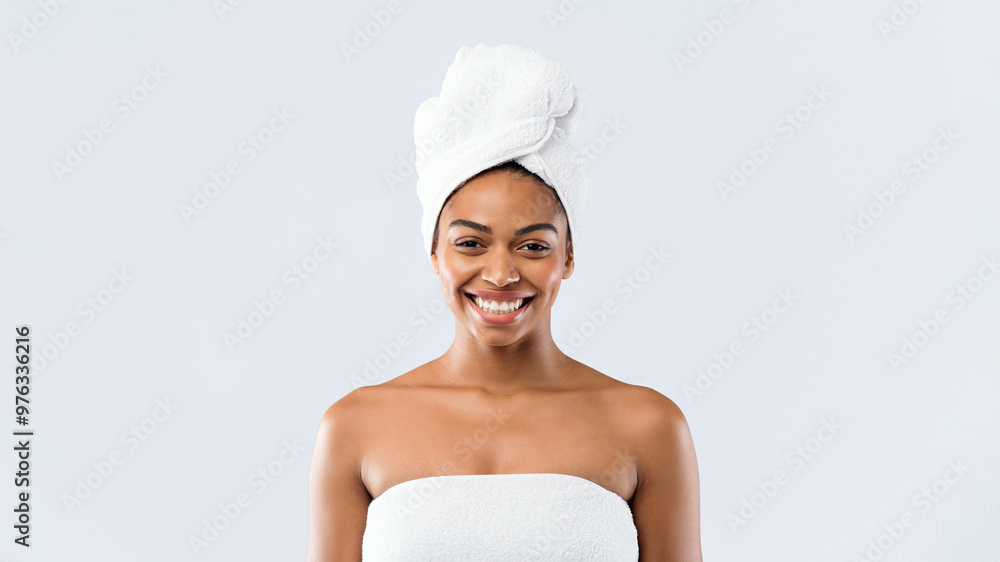 Portrait of happy young black woman wrapped in bath towels over grey studio background Portrait of happy young black woman wrapped in bath towels over grey studio background