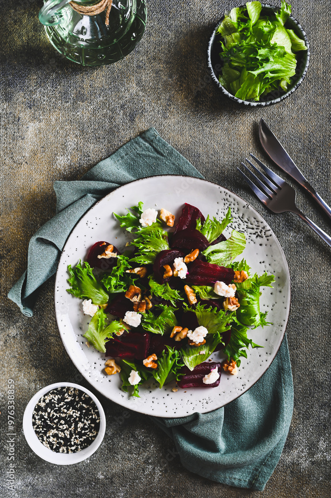 Beetroot salad with cheese, nuts and herbs on a plate on the table top and vertical view