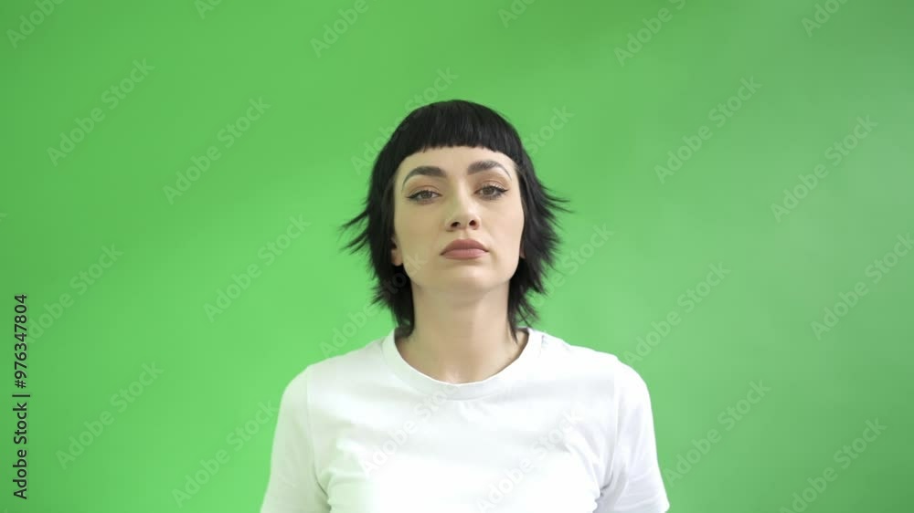 Woman With Striking Black Hair Shaking Head Side to Side While Crossing Her Arms Against Vivid Green Backdrop Woman With Striking Black Hair Shaking Head Side to Side While Crossing Her Arms Against Vivid Green Backdrop
