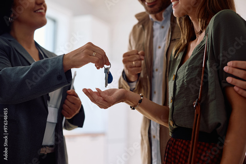 Close up of real estate agent giving new house keys to a couple of buyers.