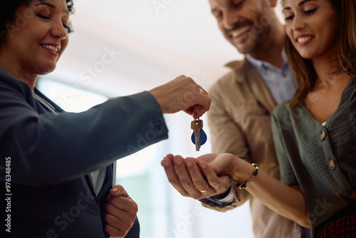 Close up of real estate agent giving new house keys to couple of buyers. photo