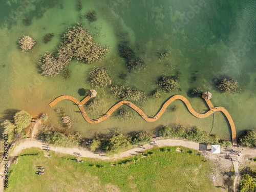 Aerial drone photo of Quarry turquiose lake colour, open pit mining in Park Grodek, Jaworzno. Poland. Turquiose Water and Wooden Bridge on lake. Polish Maldives Park Grodek in Jaworzno from drone. photo