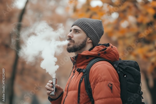 man enjoying a vape outdoors in autumn, wrapped in a colorful scarf surrounded by fall foliage