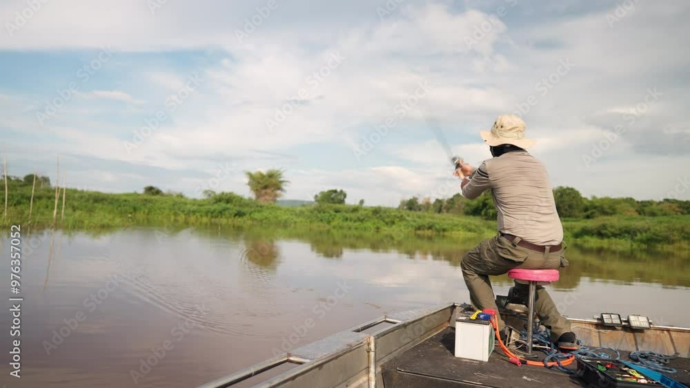 A man is fishing in a boat on a lake. The man is wearing a hat and a bandana A man is fishing in a boat on a lake. The man is wearing a hat and a bandana