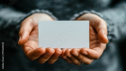 Person holding a blank business card in hands with a soft background during d...