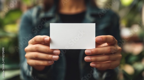Person holding a blank business card in hands with a soft background during d...