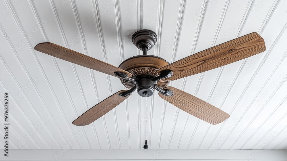 Ceiling fan with wooden blades in a bright, airy room with large windows and white walls Ceiling fan with wooden blades in a bright, airy room with large windows and white walls