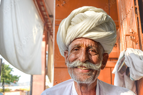 Foto Elderly man with mustache and traditional Rajasthani turban smiling to camera