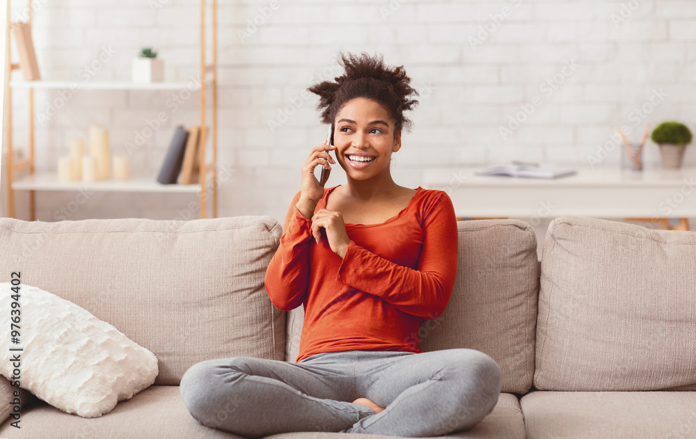 Fototapeta premium Phone Talk. Smiling Afro Woman Chatting On Cellphone Sitting On Couch At Home On Weekend.