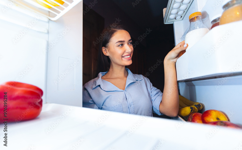 Millennial woman taking vegetal milk bottle from fridge, view from inside Millennial woman taking vegetal milk bottle from fridge, view from inside