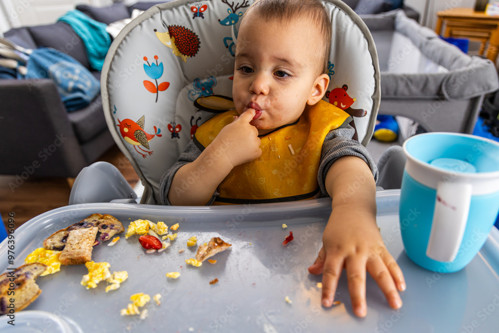 Adorable Baby Enjoying Meal Time with Finger Foods at Home in High Chair