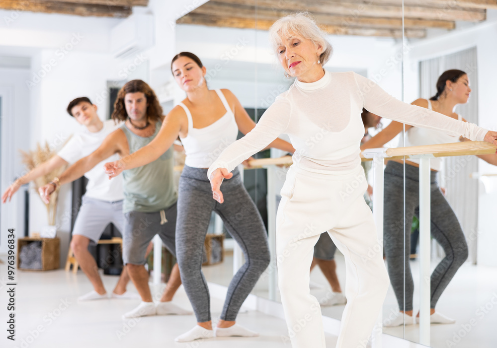 Fototapeta premium Group of people of different ages practice ballet moves in classical dance school.