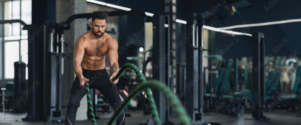 Fitness man working out with battle ropes at gym interior, free space, web-banner Fitness man working out with battle ropes at gym interior, free space, web-banner