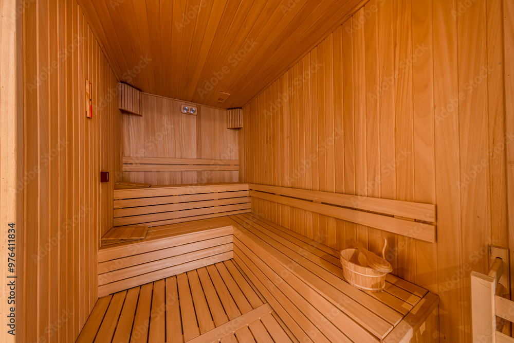 Interior of the Finnish sauna, classic wooden sauna with hot steam. Sauna room at hotel SPA center. Wooden interior baths, wooden benches and sun loungers sauna accessories, spa complex. Interior of the Finnish sauna, classic wooden sauna with hot steam. Sauna room at hotel SPA center. Wooden interior baths, wooden benches and sun loungers sauna accessories, spa complex.