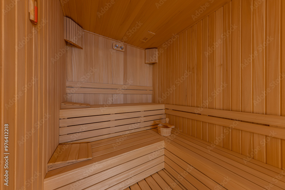 Interior of the Finnish sauna, classic wooden sauna with hot steam. Sauna room at hotel SPA center. Wooden interior baths, wooden benches and sun loungers sauna accessories, spa complex. Interior of the Finnish sauna, classic wooden sauna with hot steam. Sauna room at hotel SPA center. Wooden interior baths, wooden benches and sun loungers sauna accessories, spa complex.