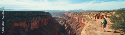 Aerial view of an explorer hiking along the edge of a deep canyon, red rock formations stretching below, epic sense of adventure and scale