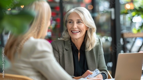 Fototapeta Naklejka Na Ścianę i Meble -  Smiling mature business woman hr holding cv document at job interview. Happy mid aged professional banking manager or lawyer consulting client sitting at workplace in corporate office meeting.