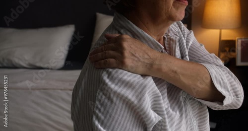 Old woman suffering from neck. An older woman massages the muscles of her shoulder and neck. An older woman massages the muscles of her shoulder and neck to relieve severe pain.