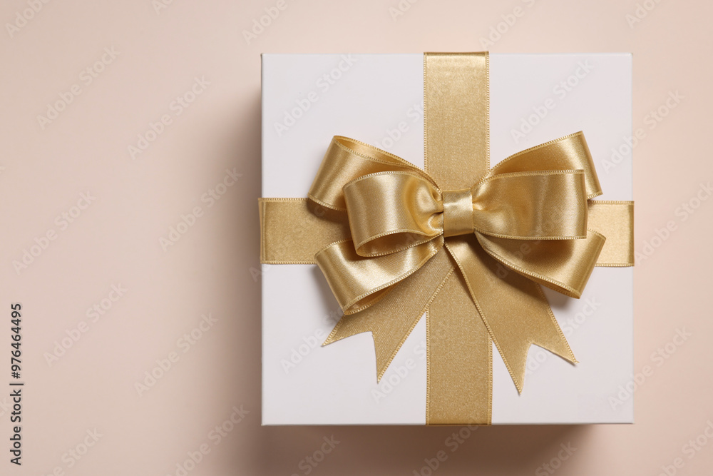 Gift box with bow on beige background, top view Gift box with bow on beige background, top view