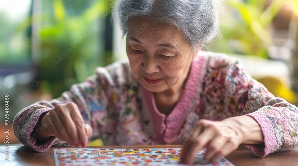 Alzheimer disease AD Asian elderly woman playing sudoku puzzle game to practice for dementia prevention. Alzheimer disease AD Asian elderly woman playing sudoku puzzle game to practice for dementia prevention.