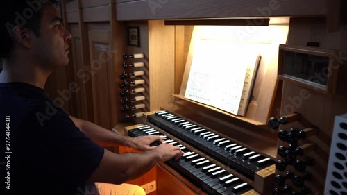 Right side view of organist playing organ in Catholic Church.