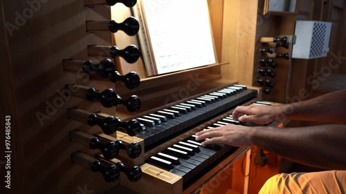 Left side view of Organist's hands playing organ in Catholic Church.