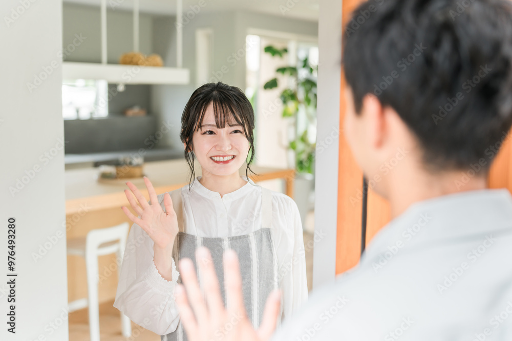 Fototapeta premium 朝出勤する夫・旦那を笑顔で見送りする若いアジア人女性・妻 