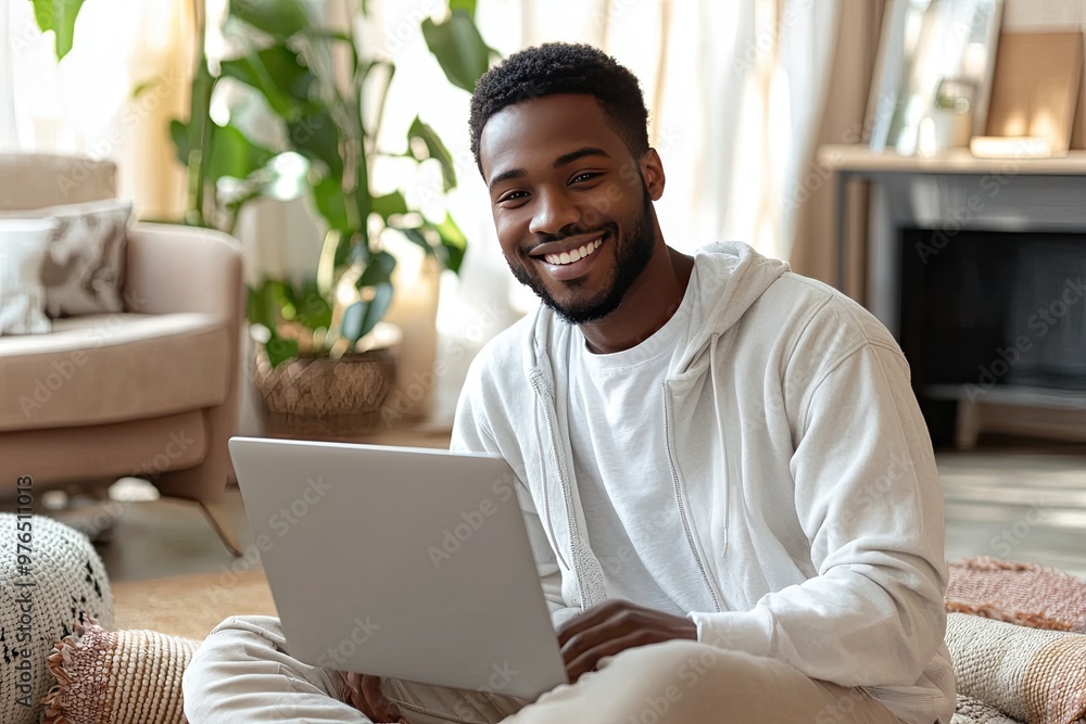 Happy man using laptop at home, smiling and enjoying his time in a cozy living room setting with natural light. Happy man using laptop at home, smiling and enjoying his time in a cozy living room setting with natural light.