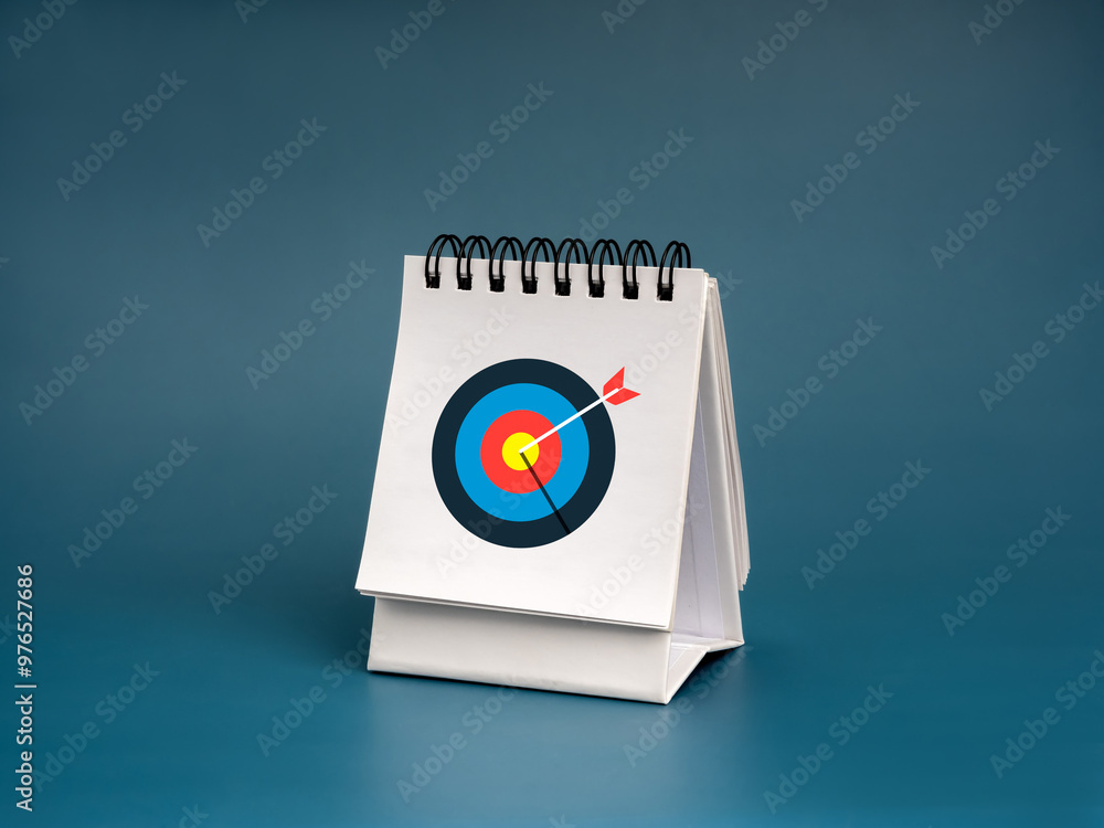 Modern colorful target dart bullseye icon on white desk calendar cover isolated on dark blue background. Business goal and success, scheduled, agenda, action plan concepts in new year. Modern colorful target dart bullseye icon on white desk calendar cover isolated on dark blue background. Business goal and success, scheduled, agenda, action plan concepts in new year.