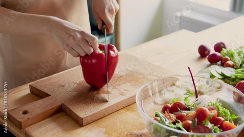 Organic food. Woman cutting red bell pepper at kitchen board, close up