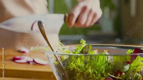 Woman cutting fresh radish for vegetable salad at kitchen, mixing it, close up