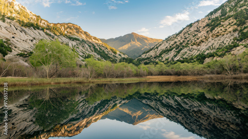 A photo of a serene landscape with a calm lake reflecting the surrounding mountains and trees. The mountains have a rocky terrain and are covered with greenery. There are trees near the lake.