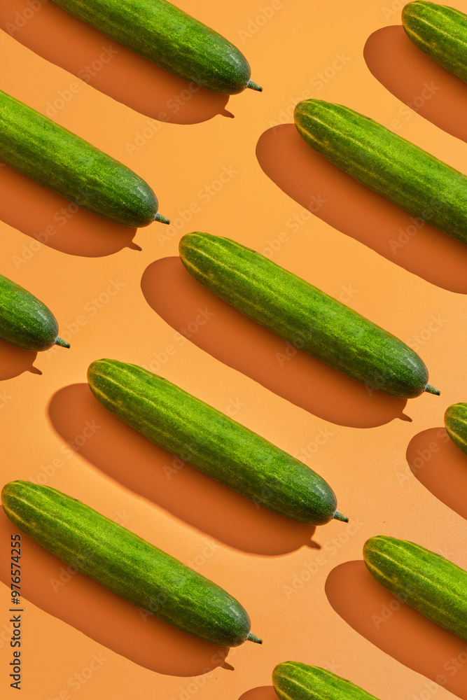 Green cucumbers on orange background arranged diagonally; ideal for food blogs, cooking websites, healthy lifestyle content, and culinarythemed designs. Green cucumbers on orange background arranged diagonally; ideal for food blogs, cooking websites, healthy lifestyle content, and culinarythemed designs.