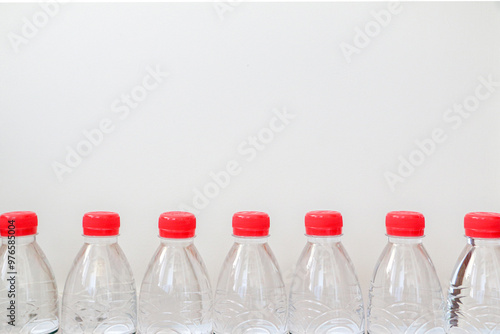 Clear plastic bottled water with red caps lined against white background. Healthy lifestyle and hydration concept.