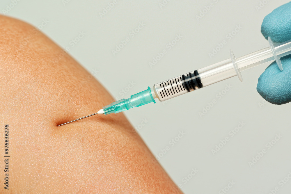 Close-up of a patient's arm with a syringe administering a flu shot Close-up of a patient's arm with a syringe administering a flu shot