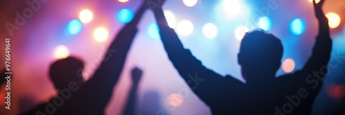 Silhouettes of people raising their hands while enjoying a live music concert with vibrant, colorful lights in the background, symbolizing excitement and unity. photo